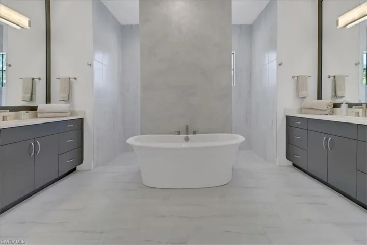 Bathroom featuring two vanities and a freestanding tub plus carwash style shower