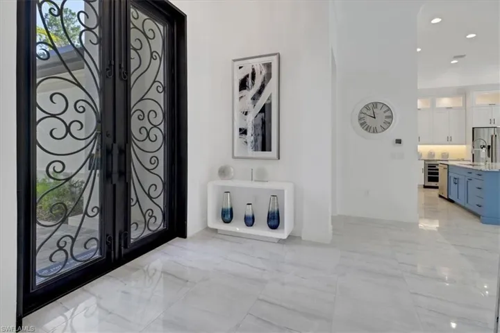 Foyer with light porcelain tile floors, 10' iron-clad decorative front doors