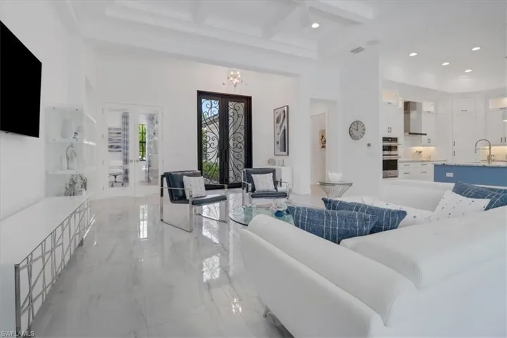 Great room showing 10' iron-clad entry doors, light porcelain tile floors, boxed coffered ceiling, a ceiling fan, recessed lighting, and 12' celilings