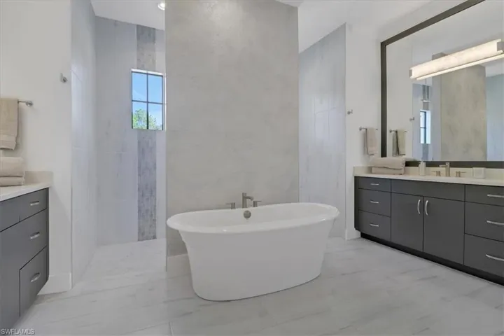 Owner's bathroom featuring two vanities, a freestanding tub, and a carwash style walk-in shower