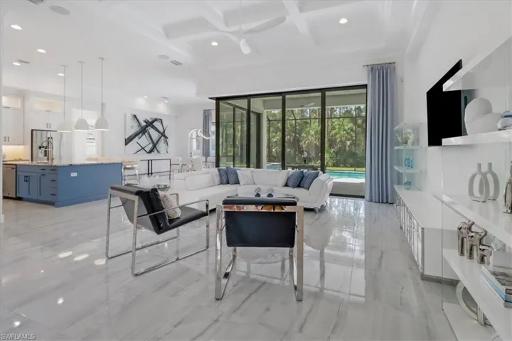 Great room featuring seven-panel 90 degree pocketing slider, light porcelain tile floors, boxed coffered ceiling, a ceiling fan, recessed lighting, and 12' celilings