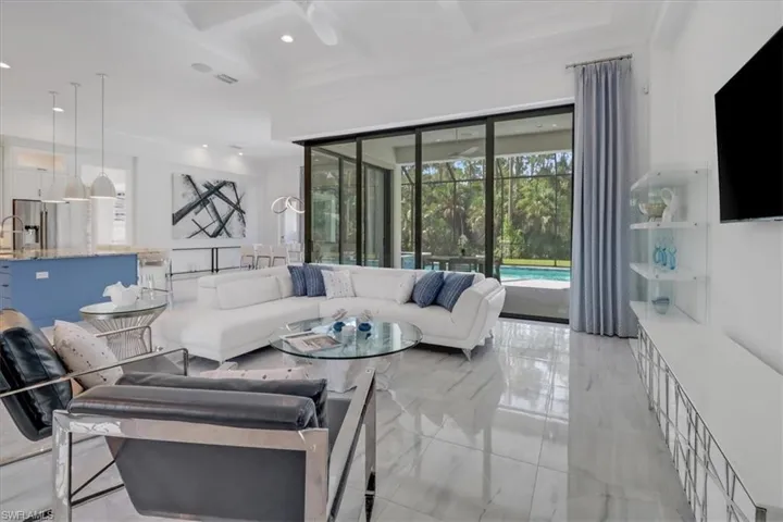 Great room featuring seven-panel 90-degree pocketing slider, light porcelain tile floors, boxed coffered ceiling, a ceiling fan, recessed lighting, and 12' celilings