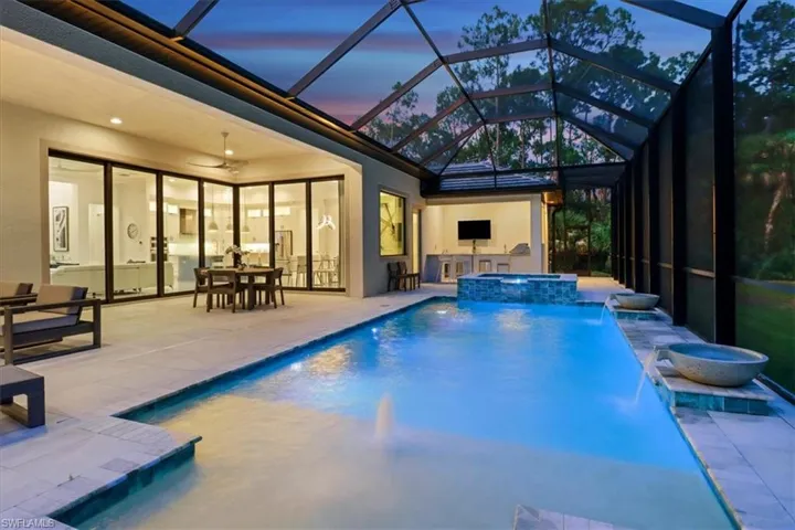 View of swimming pool with a pool with connected hot tub, a patio, and glass enclosure