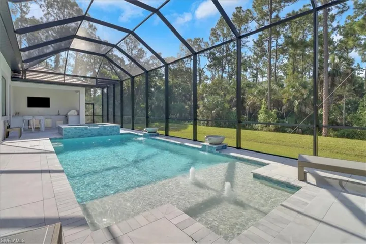 View of pool with screen cage overlooking the heavily treed backyard