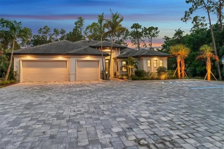 View of front of house featuring a garage, stucco siding, and decorative driveway
