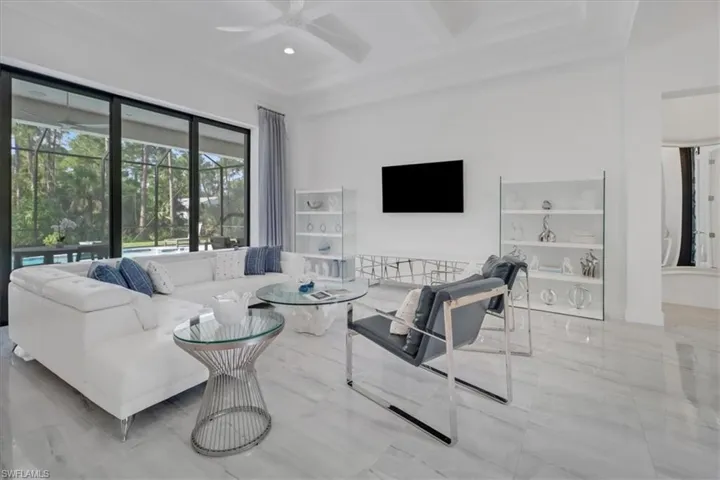 Great room featuring seven-panel 90-degree pocketing slider, light porcelain tile floors, boxed coffered ceiling, a ceiling fan, recessed lighting, and 12' celilings