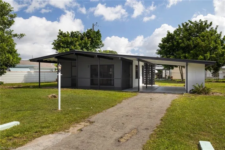 Mid-century home featuring an attached carport, a front lawn