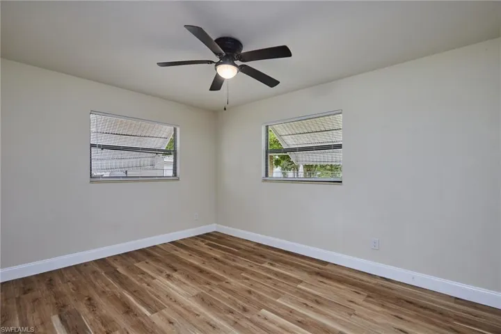Room featuring plenty of natural light, wood like finished floors, and a ceiling fan