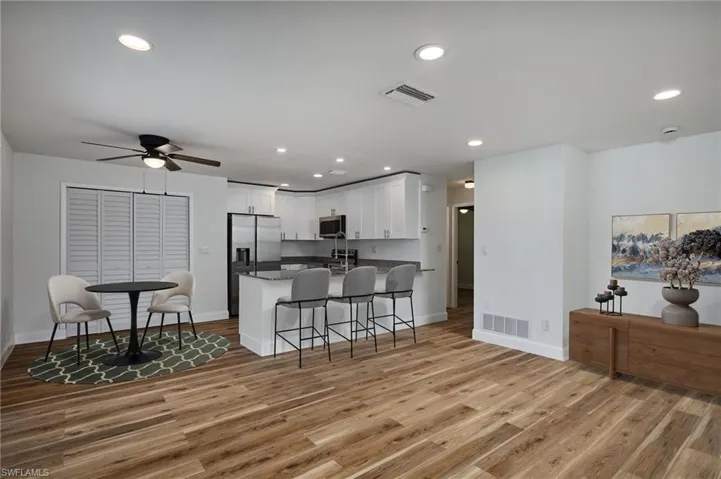 Kitchen featuring stainless steel appliances, a peninsula, white cabinets, light wood finished floors, and a ceiling fan
