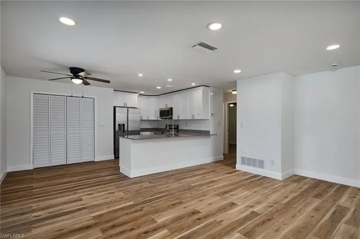 Kitchen with stainless steel appliances, white cabinetry, a ceiling fan, light wood-type flooring, and open floor plan