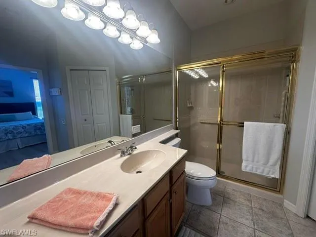 Full bath with toilet, vanity, tile patterned floors, and a stall shower