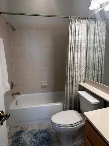 Full bathroom with tile patterned floors, shower / tub combo with curtain, vanity, and toilet
