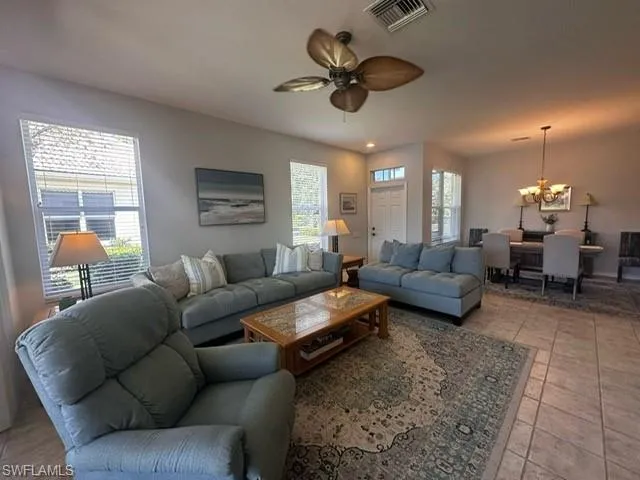Living room featuring visible vents and ceiling fan with notable chandelier