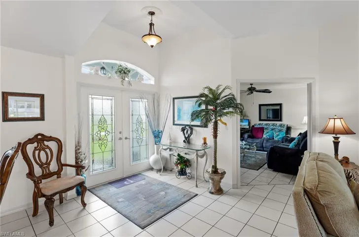 Entryway featuring french doors, healthy amount of natural light, light tile patterned floors, a towering ceiling, and a ceiling fan