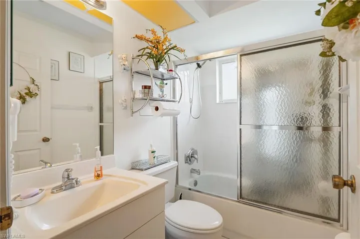 Bathroom with vanity and combined bath / shower with glass door