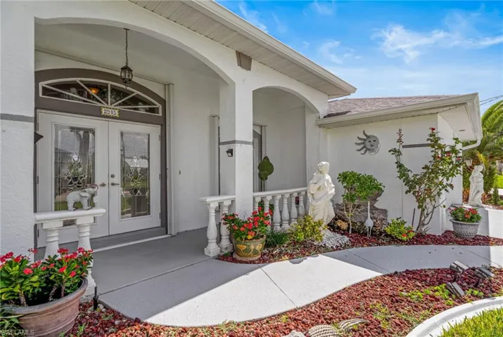 Property entrance with covered porch, stucco siding, french doors, and a shingled roof