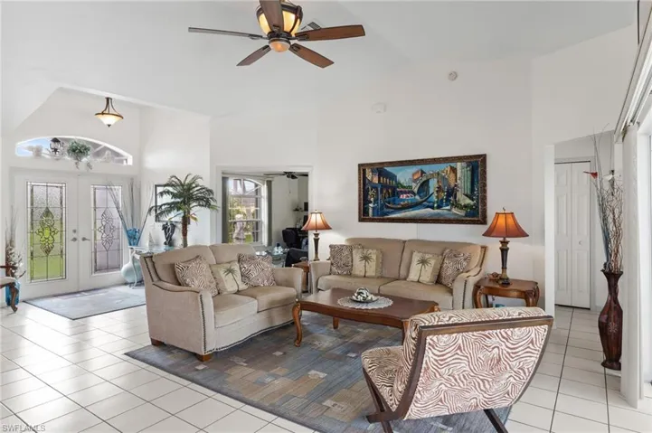 Living area with light tile patterned floors, high vaulted ceiling, a ceiling fan, and french doors