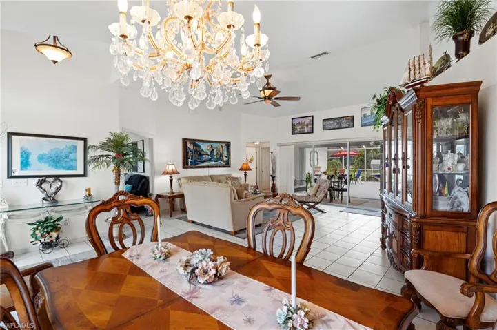 Dining area featuring light tile patterned flooring, a chandelier, a ceiling fan, and a towering ceiling
