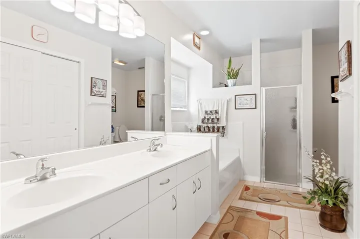 Bathroom featuring tile patterned floors, a bath, a shower stall, and double vanity