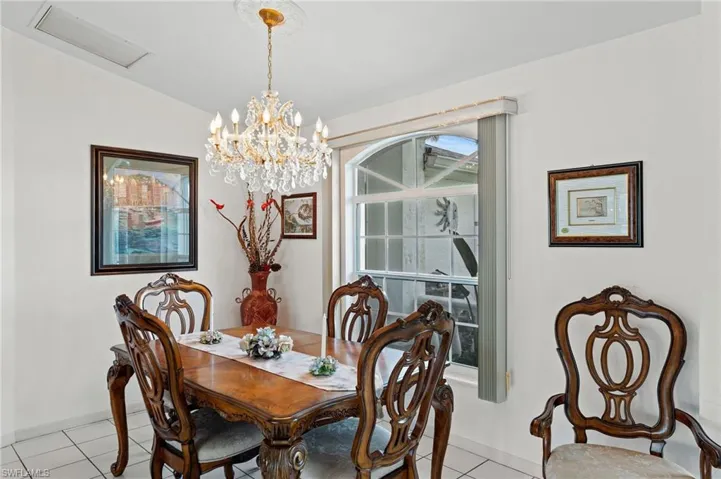 Dining space with light tile patterned flooring, vaulted ceiling, and a chandelier