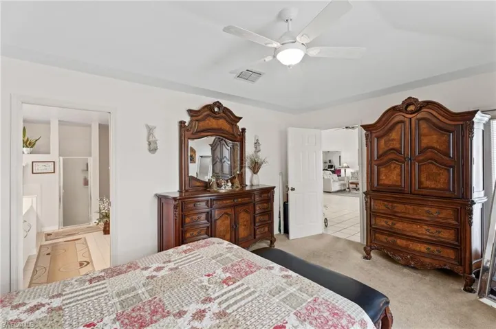 Tiled bedroom featuring carpet, connected bathroom, and a ceiling fan