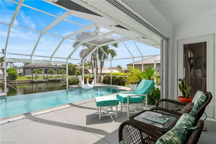 View of swimming pool featuring an infinity pool, a patio, a lanai, and a water view