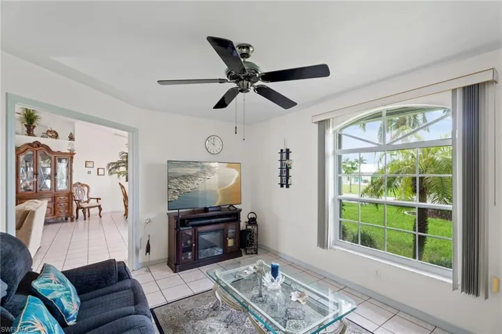 Living area featuring light tile patterned flooring, healthy amount of natural light, and ceiling fan