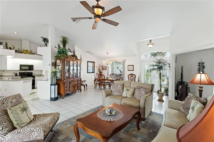 Living room featuring light tile patterned floors, a chandelier, ceiling fan, and high vaulted ceiling
