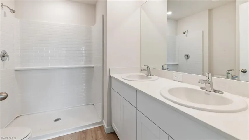 Model home. Full bath with a stall shower, double vanity, and light wood-type flooring