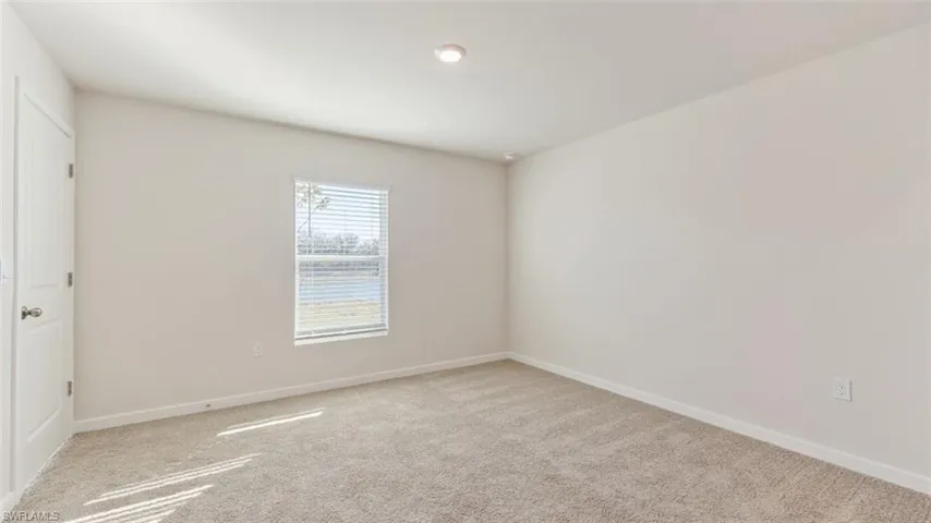 Model home. Spare room featuring baseboards and light colored carpet
