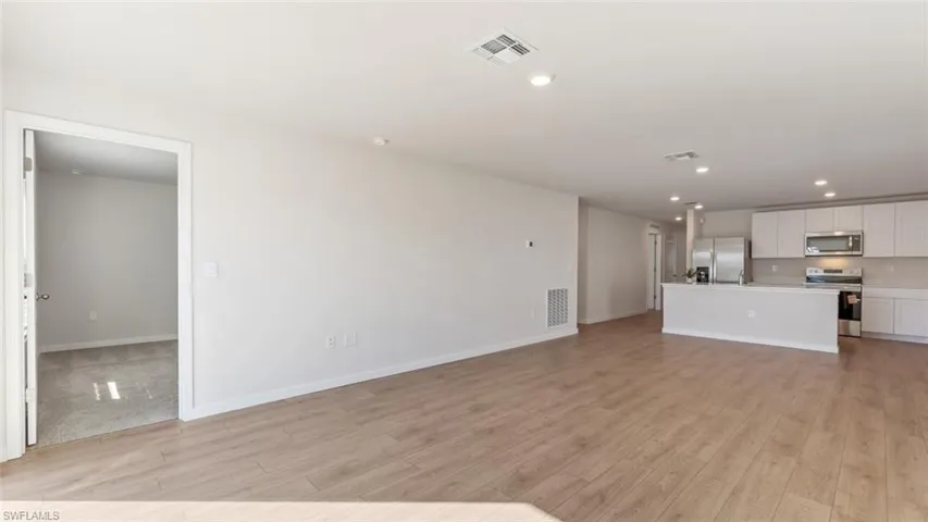 Model home. Unfurnished living room with recessed lighting and light wood-type flooring