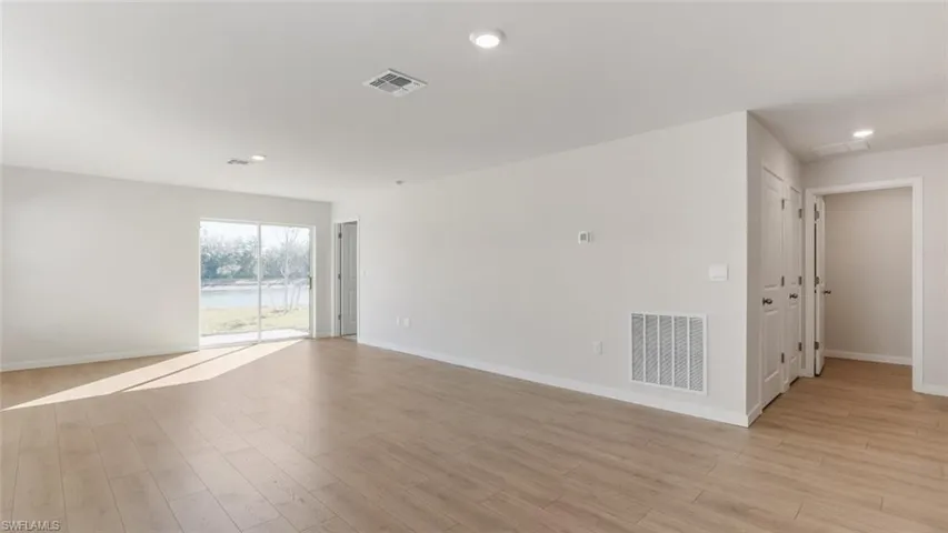 Model home. Empty room with light wood finished floors, recessed lighting, and a water view