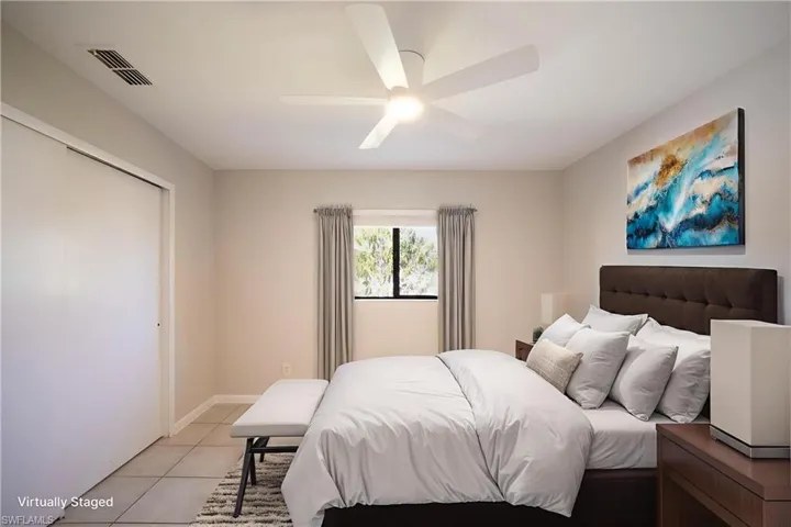 Bedroom with light tile patterned floors, ceiling fan, and a closet