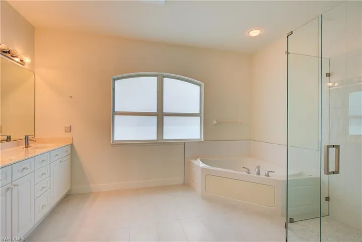 Bathroom featuring double vanity, a garden tub, a shower stall, and light tile patterned floors