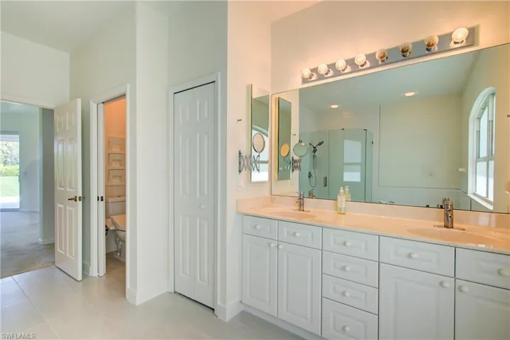 Bathroom with plenty of natural light, a closet, a stall shower, and double vanity
