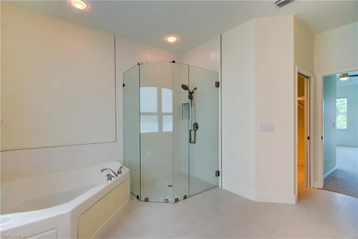 Full bathroom with a shower stall, a garden tub, light tile patterned flooring, and a spacious closet