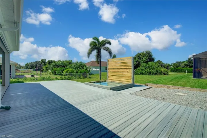 Deck featuring a lawn, view of wooded area, and a hot tub