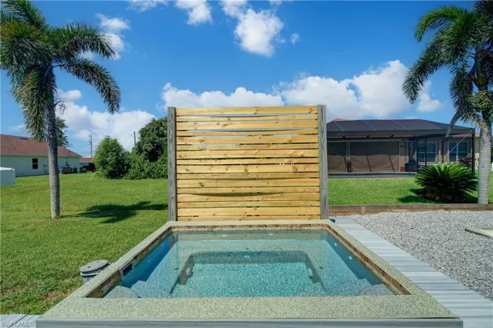 View of swimming pool with a lawn, a sunroom, a lanai, and an in-ground hot tub