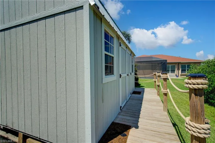 View of side of property featuring a yard, a lanai, a deck, and a sunroom