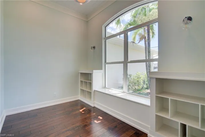 Empty room with crown molding and dark wood-type flooring