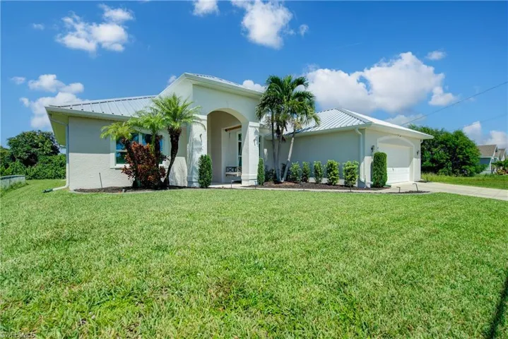 View of front of house featuring a metal roof, driveway, an attached garage, and a standing seam roof