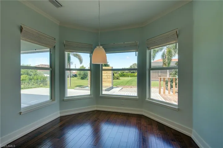 Unfurnished dining area with dark wood-type flooring and ornamental molding
