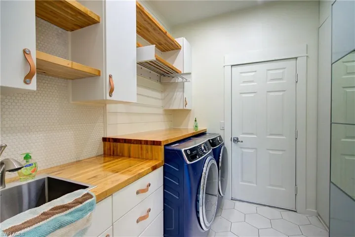 Laundry room with light tile patterned floors, independent washer and dryer, and cabinet space