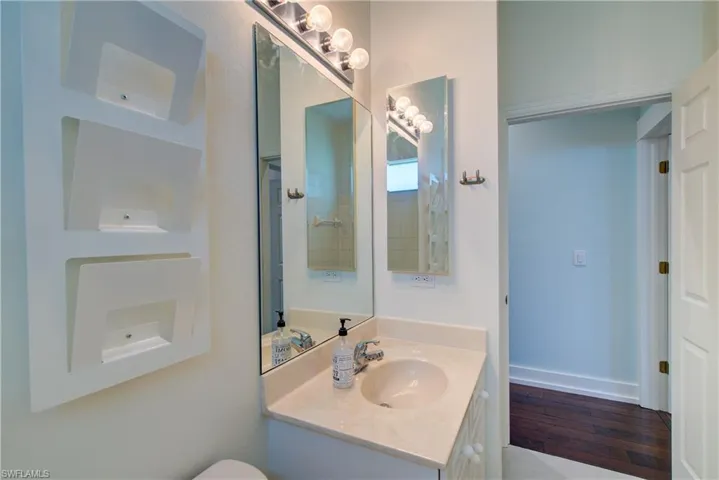 Half bath featuring vanity, built in features, and dark wood finished floors
