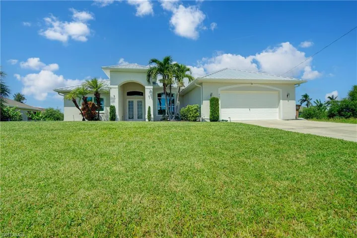 Mediterranean / spanish home featuring driveway, stucco siding, a metal roof, an attached garage, and a front yard