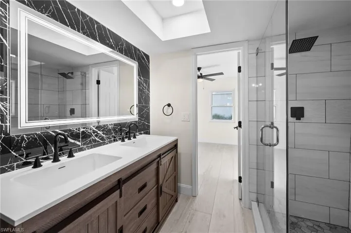 Bathroom with a stall shower, a sink, and decorative backsplash