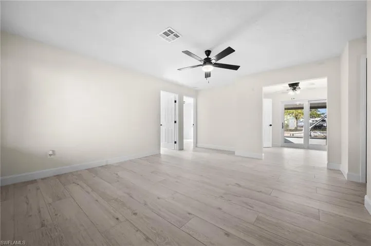 Empty room with baseboards, ceiling fan, visible vents, and light wood-style floors