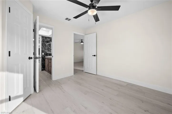 Unfurnished bedroom with light wood finished floors, baseboards, visible vents, and ceiling fan