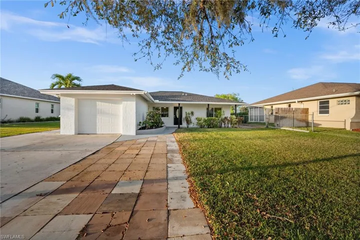 Single story home with a garage, fence, driveway, stucco siding, and a front lawn