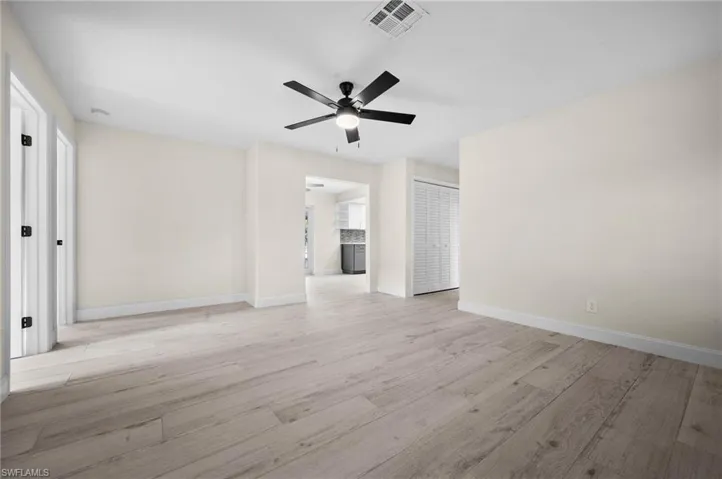 Empty room featuring a ceiling fan, visible vents, light wood-style flooring, and baseboards